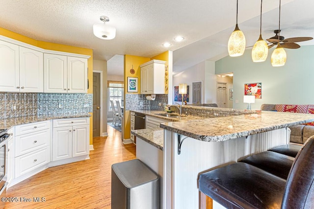 2 Beryl Cir, Pinehurst, NC 28374 - kitchen featuring a breakfast bar area, light wood-style flooring, a peninsula, a sink, and backsplash