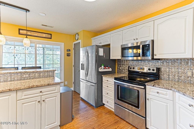 2 Beryl Cir, Pinehurst, NC 28374 - kitchen featuring appliances with stainless steel finishes, light wood finished floors, backsplash, and white cabinetry
