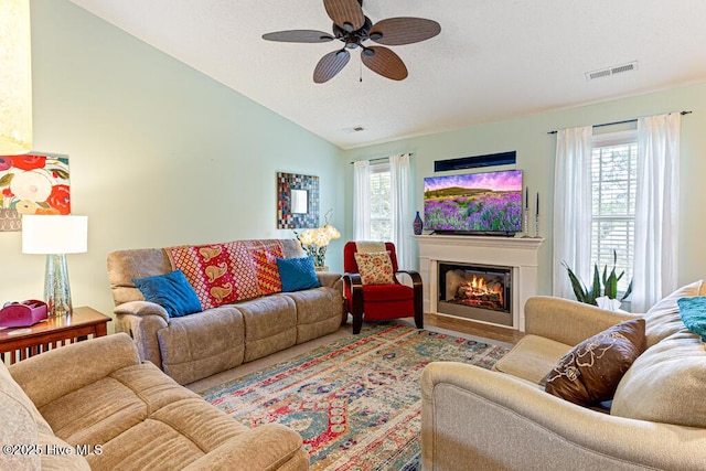 2 Beryl Cir, Pinehurst, NC 28374 - living room with vaulted ceiling, a ceiling fan, a glass covered fireplace, and a textured ceiling