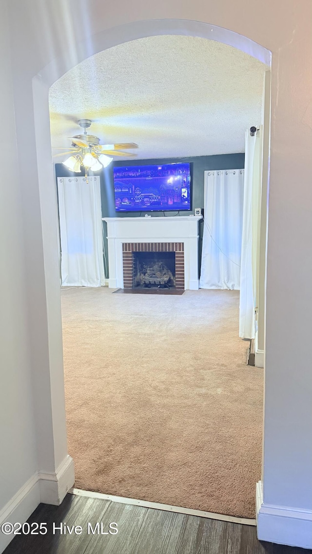 308 Terry St, Hamlet, NC 28345 - unfurnished living room featuring ceiling fan, a fireplace, carpet flooring, baseboards, and a textured ceiling