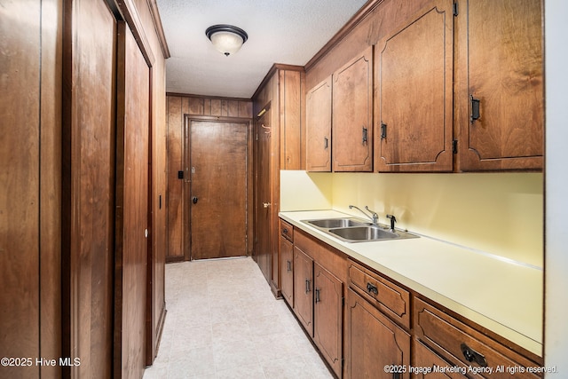 1363 Robert Everett Rd, Robersonville, NC 27871 - kitchen featuring a sink, light countertops, a textured ceiling, wooden walls, and brown cabinets