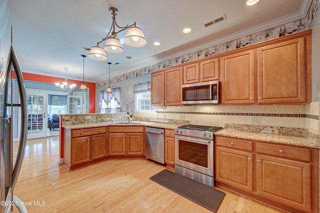 4029 Berberis Way, Wilmington, NC 28412 - kitchen with stainless steel appliances, a chandelier, a sink, a peninsula, and light wood-style floors