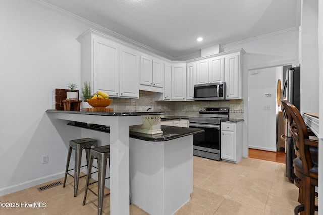 3 Merion Cir, Pinehurst, NC 28374 - kitchen with stainless steel appliances, dark countertops, a peninsula, white cabinetry, and ornamental molding