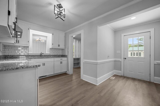 306 Oak Dr, Tarboro, NC 27886 - kitchen with a chandelier, white cabinets, light wood finished floors, tasteful backsplash, and ornamental molding