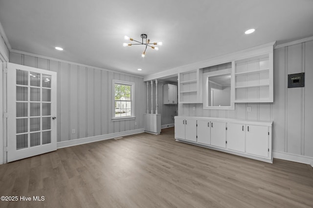 306 Oak Dr, Tarboro, NC 27886 - unfurnished living room featuring a chandelier, wood finished floors, crown molding, a decorative wall, and baseboards