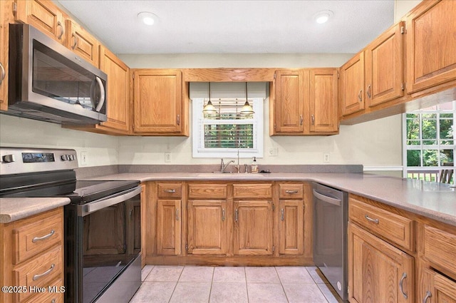 2 Pinewood Dr, Calabash, NC 28467 - kitchen featuring stainless steel appliances, a sink, light countertops, light tile patterned flooring, and brown cabinets