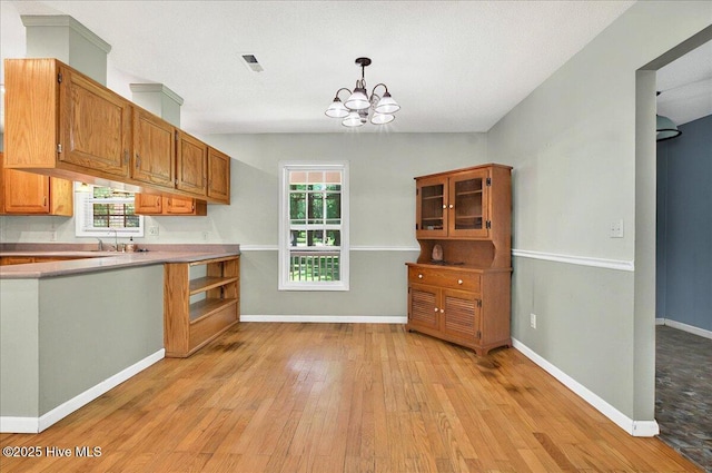 2 Pinewood Dr, Calabash, NC 28467 - kitchen with light wood-style flooring, a chandelier, healthy amount of natural light, and light countertops