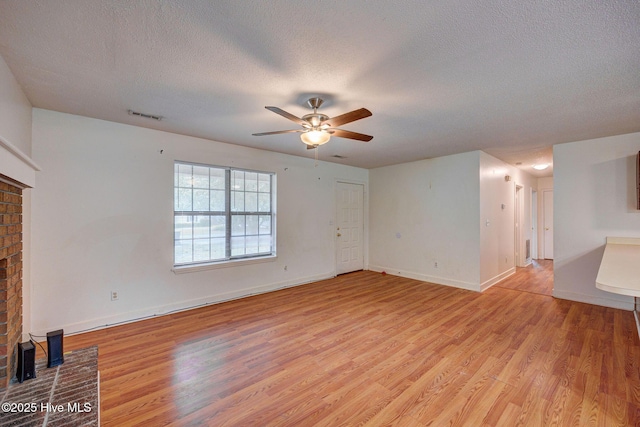 4448 Jamey Ct, Wilmington, NC 28405 - unfurnished living room with a ceiling fan, a textured ceiling, light wood-style flooring, a fireplace, and baseboards