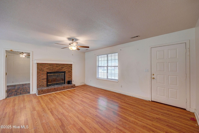 4448 Jamey Ct, Wilmington, NC 28405 - unfurnished living room featuring ceiling fan, light wood-type flooring, a textured ceiling, a brick fireplace, and baseboards