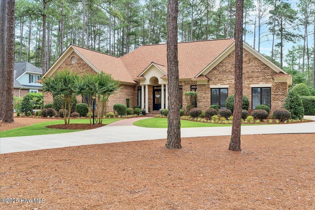 21 Abbottsford Dr, Pinehurst, NC 28374 - view of front of house featuring brick siding, curved driveway, and roof with shingles