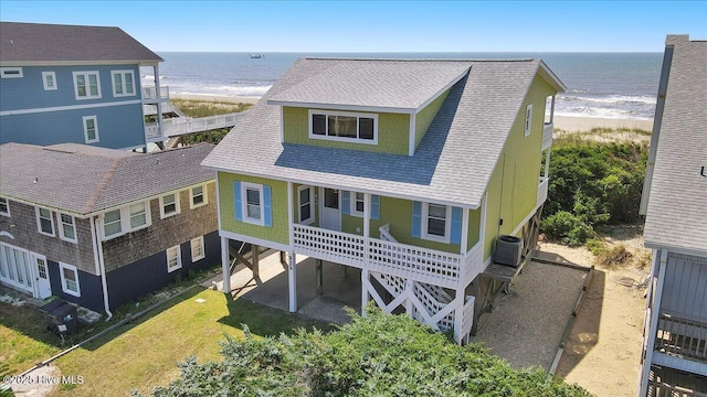 939 Ocean Blvd W, Holden Beach, NC 28462 - view of front facade with view of water and beach, central AC unit, roof with shingles, and a porch