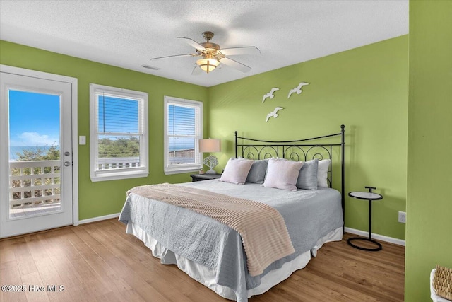 939 Ocean Blvd W, Holden Beach, NC 28462 - bedroom with access to exterior, wood finished floors, baseboards, ceiling fan, and a textured ceiling