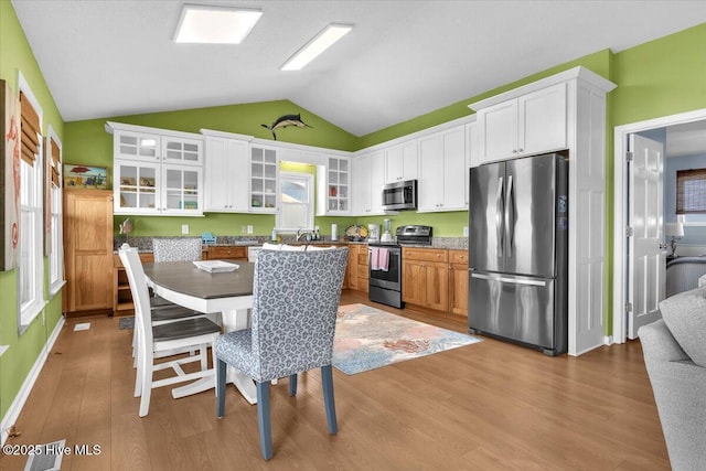 939 Ocean Blvd W, Holden Beach, NC 28462 - kitchen with appliances with stainless steel finishes, vaulted ceiling, wood finished floors, white cabinetry, and glass insert cabinets