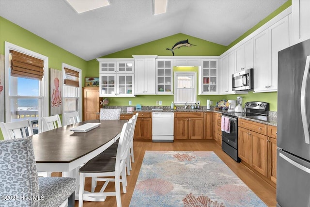 939 Ocean Blvd W, Holden Beach, NC 28462 - kitchen featuring appliances with stainless steel finishes, vaulted ceiling, light wood-style floors, glass insert cabinets, and white cabinets