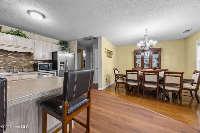 119 Cobblestone Trl, Jacksonville, NC 28546 - kitchen featuring appliances with stainless steel finishes, a sink, wood finished floors, a chandelier, and backsplash