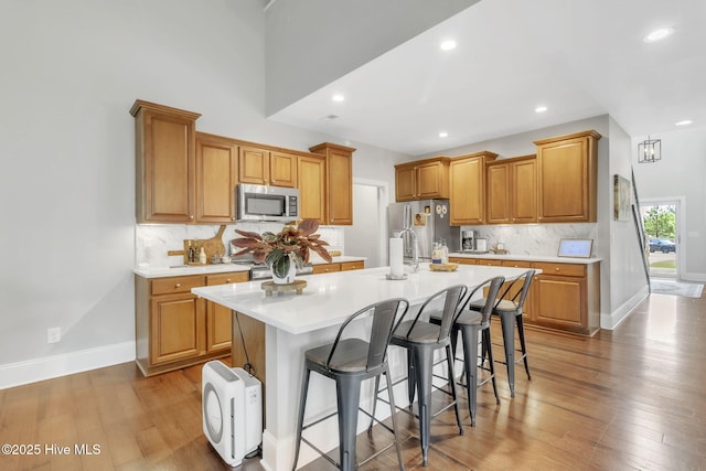 115 Norman Cir, Aberdeen, NC 28315 - kitchen featuring stainless steel appliances, light countertops, an island with sink, decorative backsplash, and light wood-style floors