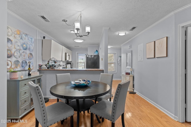 1825 Savannah Ct Unit D3, Wilmington, NC 28403 - dining space featuring ornamental molding, a textured ceiling, light wood-style floors, a chandelier, and baseboards
