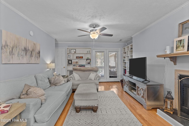 1825 Savannah Ct Unit D3, Wilmington, NC 28403 - living room with ceiling fan, light wood-type flooring, a textured ceiling, a fireplace with raised hearth, and crown molding