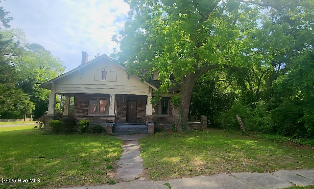 301 S Commerce St, Aulander, NC 27805 - view of front of home featuring a front lawn, a porch, and brick siding