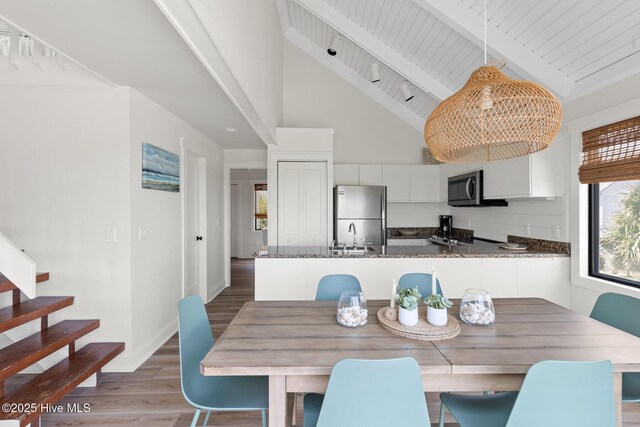 305 S Bald Head Wynd Wynd Unit 16, Bald Head Island, NC 28461 - dining area featuring high vaulted ceiling, light wood-style flooring, stairway, beam ceiling, and baseboards