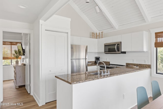 305 S Bald Head Wynd Wynd Unit 16, Bald Head Island, NC 28461 - kitchen featuring appliances with stainless steel finishes, a peninsula, dark stone counters, a sink, and white cabinets