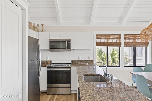 305 S Bald Head Wynd Wynd Unit 16, Bald Head Island, NC 28461 - kitchen with appliances with stainless steel finishes, a sink, white cabinets, light wood-style flooring, and dark stone countertops