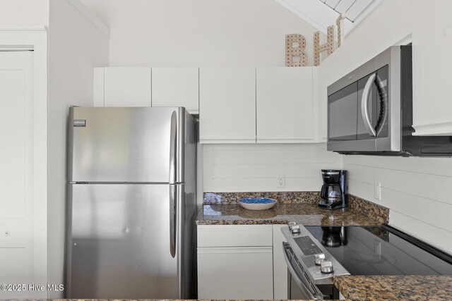 305 S Bald Head Wynd Wynd Unit 16, Bald Head Island, NC 28461 - kitchen featuring appliances with stainless steel finishes, white cabinets, dark stone counters, and vaulted ceiling