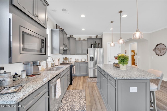 3213 Laughing Gull Ter, Wilmington, NC 28412 - kitchen featuring stainless steel appliances, gray cabinets, a sink, ornamental molding, and a kitchen island