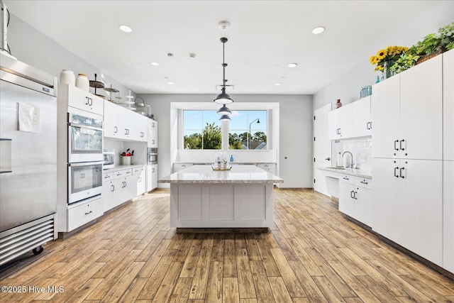 3213 Laughing Gull Ter, Wilmington, NC 28412 - kitchen with fridge, double wall oven, light wood-type flooring, a center island, and white cabinets