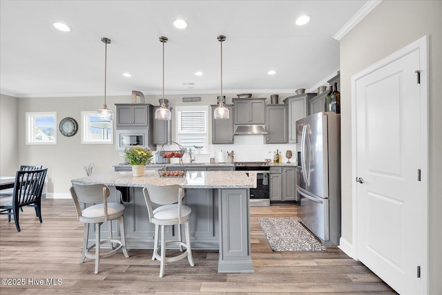 3213 Laughing Gull Ter, Wilmington, NC 28412 - kitchen featuring appliances with stainless steel finishes, gray cabinetry, under cabinet range hood, ornamental molding, and a center island