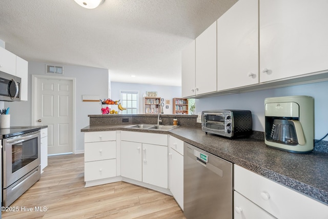 130 Woodgreen Ln, Aberdeen, NC 28315 - kitchen featuring stainless steel appliances, a sink, light wood-style floors, white cabinetry, and a textured ceiling