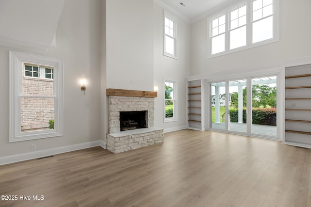 1401 Regatta Dr, Wilmington, NC 28405 - unfurnished living room featuring a towering ceiling, ornamental molding, a fireplace, light wood-type flooring, and baseboards