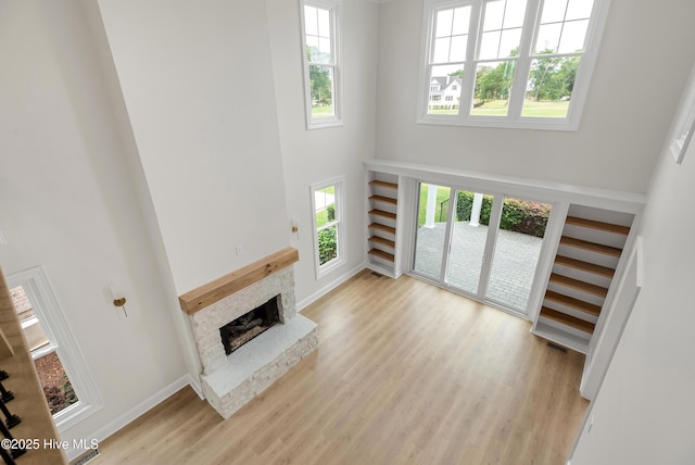 1401 Regatta Dr, Wilmington, NC 28405 - unfurnished living room with a high ceiling, a fireplace with raised hearth, light wood finished floors, and baseboards