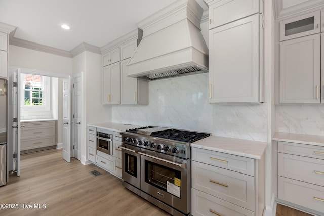 1401 Regatta Dr, Wilmington, NC 28405 - kitchen featuring double oven range, premium range hood, light countertops, crown molding, and tasteful backsplash