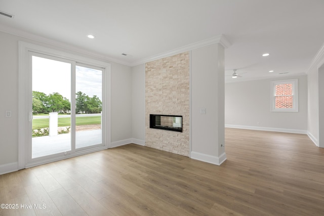 1401 Regatta Dr, Wilmington, NC 28405 - unfurnished living room featuring crown molding, wood finished floors, baseboards, a ceiling fan, and a stone fireplace