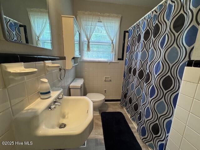 3321 US-13 N, Ahoskie, NC 27910 - bathroom with tile walls, toilet, a sink, a shower with shower curtain, and a wainscoted wall
