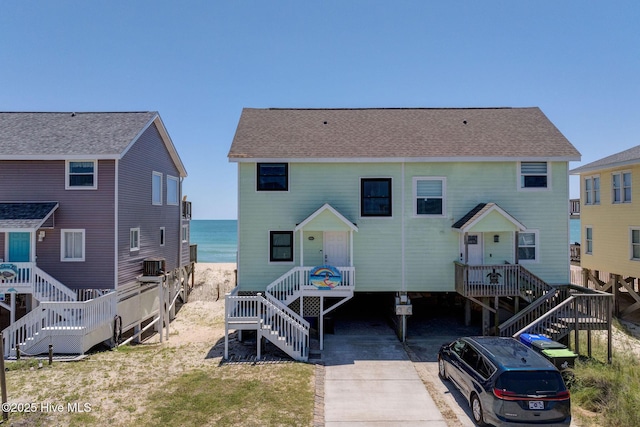 2006 N Shore Dr Unit B, Surf City, NC 28445 - rear view of house with stairs, view of water and beach, central air condition unit, and a shingled roof