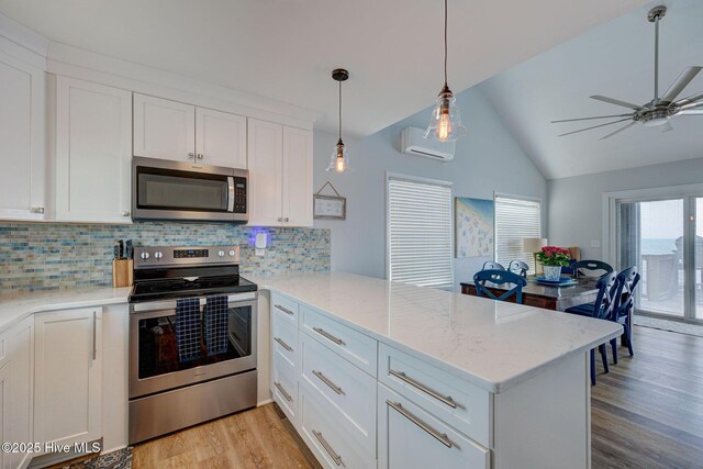 2006 N Shore Dr Unit B, Surf City, NC 28445 - kitchen featuring appliances with stainless steel finishes, a peninsula, a wall mounted air conditioner, light wood-style floors, and white cabinets