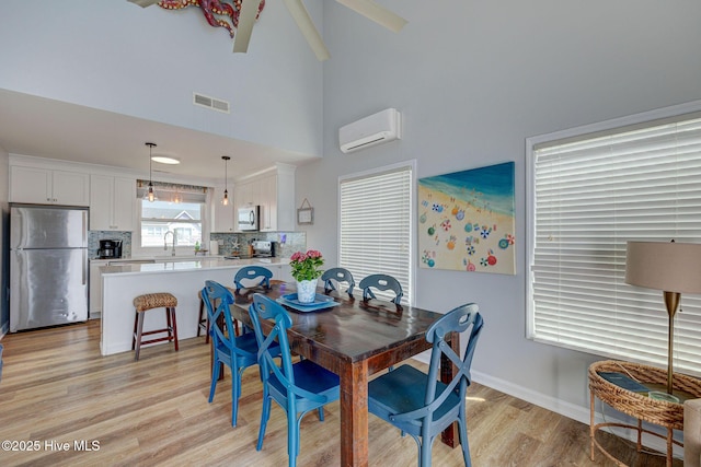 2006 N Shore Dr Unit B, Surf City, NC 28445 - dining area featuring light wood finished floors, an AC wall unit, a high ceiling, and baseboards
