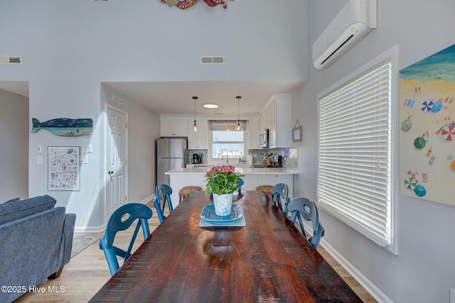 2006 N Shore Dr Unit B, Surf City, NC 28445 - dining room featuring a wall mounted AC, light wood-style flooring, and baseboards