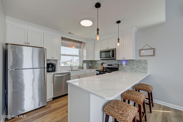 2006 N Shore Dr Unit B, Surf City, NC 28445 - kitchen with appliances with stainless steel finishes, a sink, a peninsula, light wood-style floors, and tasteful backsplash