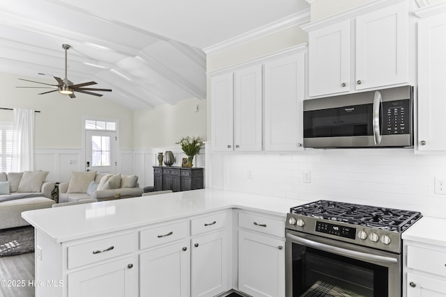2212 Lakeside Cir, Wilmington, NC 28401 - kitchen featuring appliances with stainless steel finishes, a peninsula, light countertops, white cabinets, and vaulted ceiling