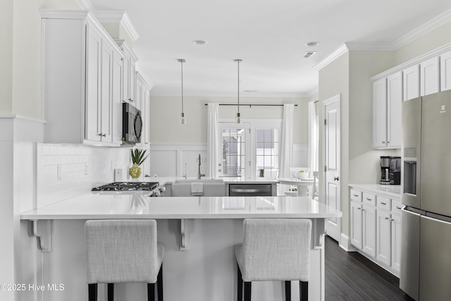 2212 Lakeside Cir, Wilmington, NC 28401 - kitchen featuring appliances with stainless steel finishes, a peninsula, light countertops, white cabinets, and crown molding
