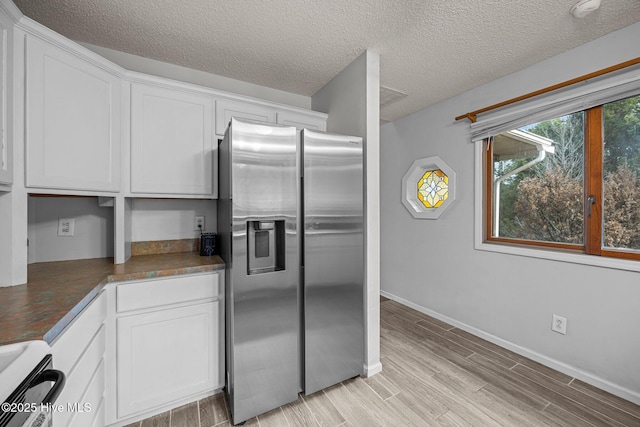 1005 Pirate Cove Cir, Oriental, NC 28571 - kitchen with stainless steel refrigerator with ice dispenser, white cabinets, dark countertops, light wood finished floors, and baseboards