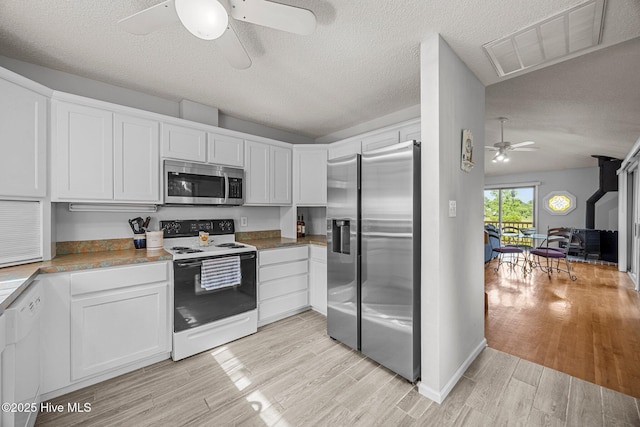 1005 Pirate Cove Cir, Oriental, NC 28571 - kitchen with appliances with stainless steel finishes, a ceiling fan, light wood-style floors, white cabinetry, and a textured ceiling