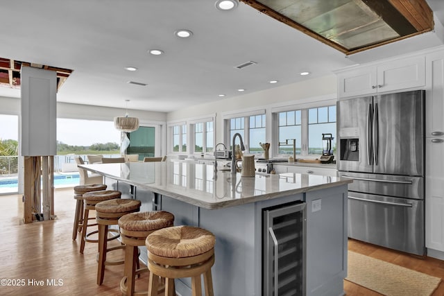 1205 Kings Lndg, Hampstead, NC 28443 - kitchen featuring stainless steel fridge with ice dispenser, wine cooler, plenty of natural light, light stone counters, and recessed lighting