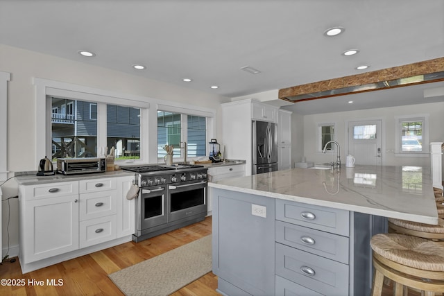 1205 Kings Lndg, Hampstead, NC 28443 - kitchen with appliances with stainless steel finishes, light stone countertops, light wood-style floors, a kitchen breakfast bar, and white cabinets