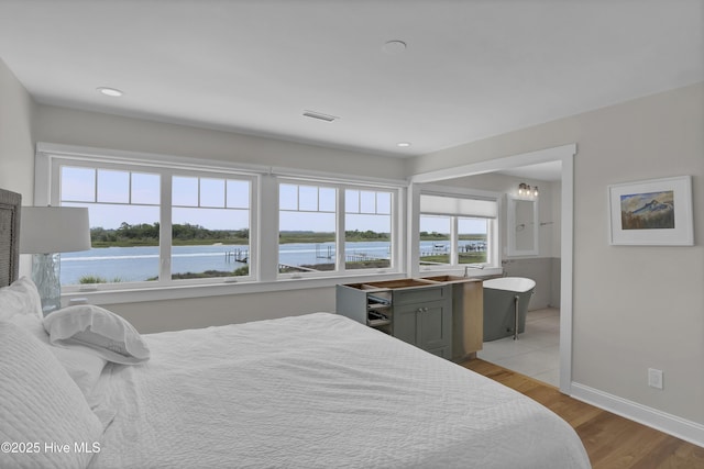 1205 Kings Lndg, Hampstead, NC 28443 - bedroom featuring multiple windows, baseboards, a water view, light wood-style floors, and recessed lighting