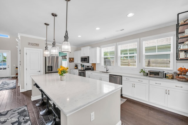 7869 Champlain Dr, Wilmington, NC 28412 - kitchen with appliances with stainless steel finishes, a sink, ornamental molding, a kitchen island, and white cabinets
