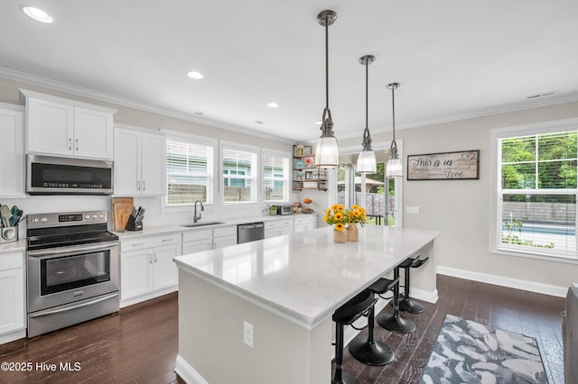 7869 Champlain Dr, Wilmington, NC 28412 - kitchen with appliances with stainless steel finishes, a sink, a kitchen island, dark wood-type flooring, and a kitchen bar